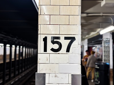 NYC Subway Platform - A white brick column at a subway station with black numbers