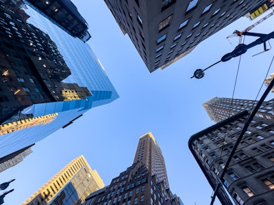 Looking Up at New York City Buildings - Looking up at tall buildings with many windows under a blue sky