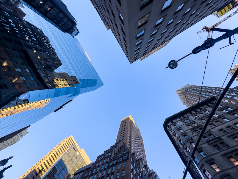 Photo: Looking up at tall buildings with many windows under a blue sky