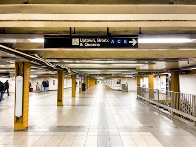 New York City Subway Station - A subway station with stairs, signs, and people walking