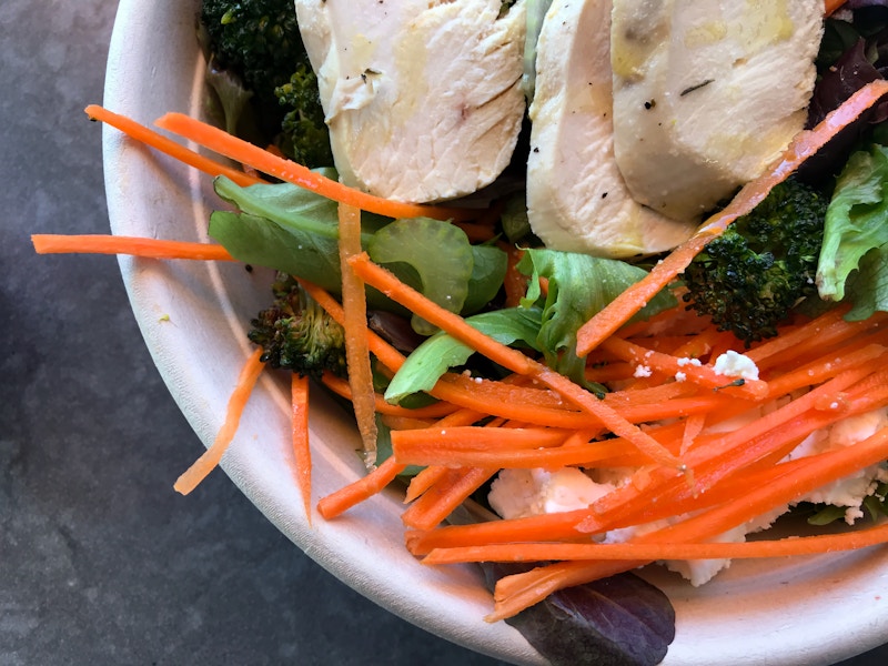 Photo: A bowl of a salad with vegetables and chicken on a table