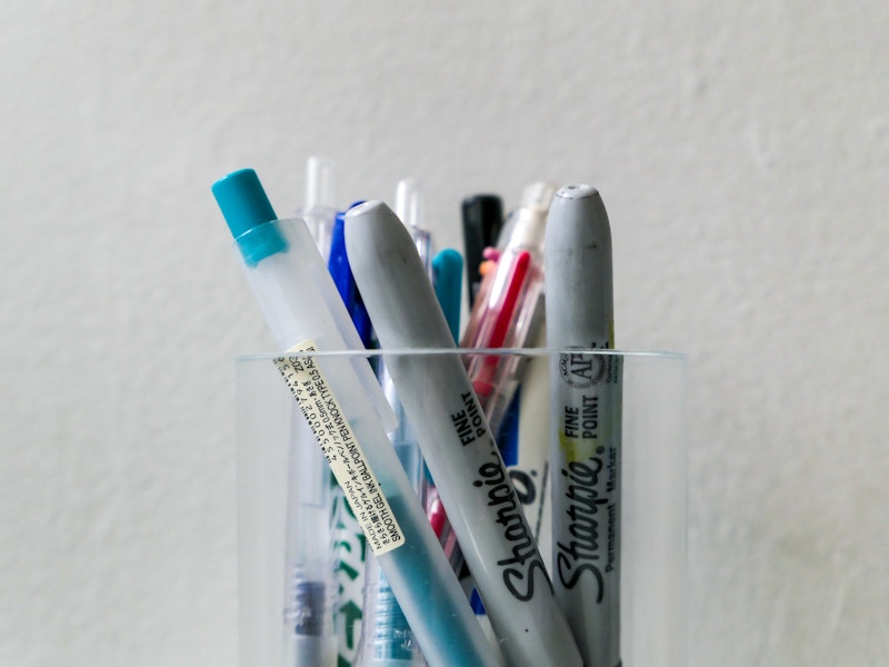 Photo: A group of pens and markers in a glass