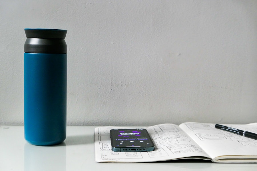 Photo: A phone and a blue coffee tumbler on a book