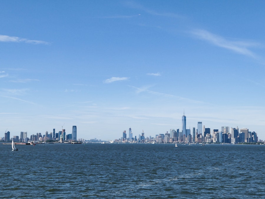 Photo: A body of water with a city skyline in the background under blue sky 