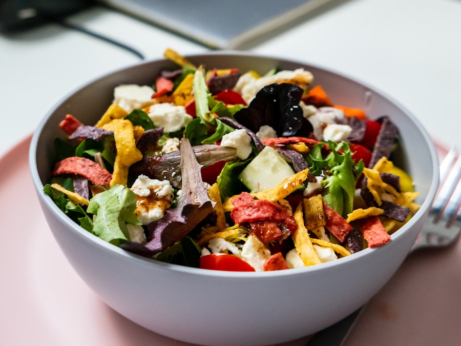 Photo: A bowl of salad with vegetables and cheese on a counter