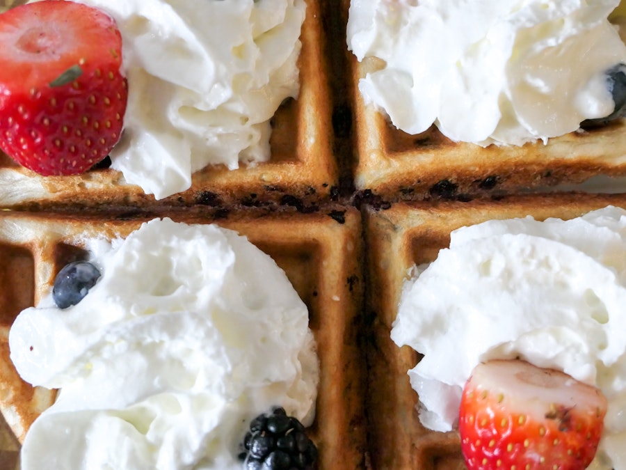 Photo: A close up of a waffle with a strawberry and whipped cream