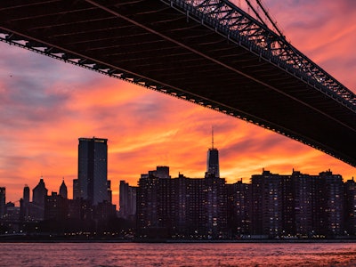 New York City Skyline and Bridge in Sunset - A bridge over water with a city and sunset in the background