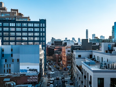 Brooklyn Street and Buildings Under Blue Sky - A city street with cars and buildings looking from a bridge 