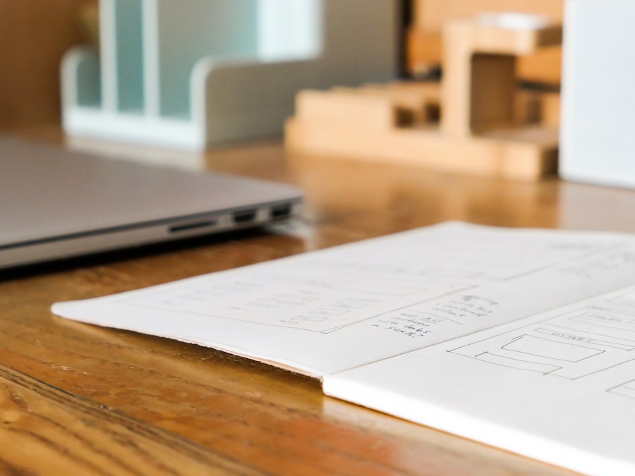 Photo: A notebook in focus and a blurred laptop on a wooden desk