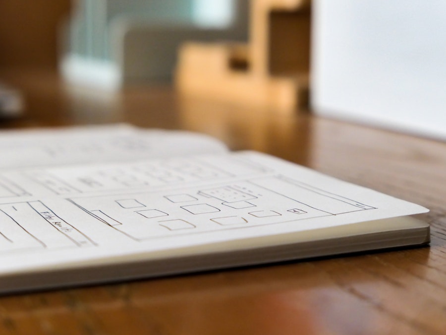 Photo: A focused close-up of a sketchbook on a wooden desk