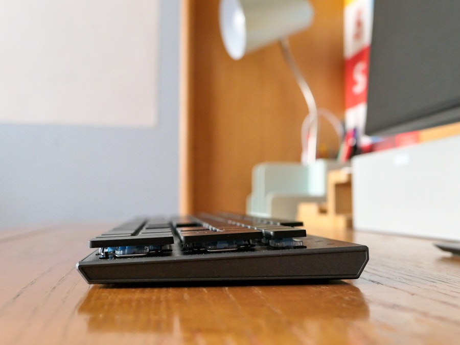 Photo: A keyboard on a wooden desk with a monitor and speaker on the side