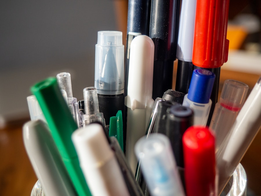 Photo: A group of pens in a cup on a desk