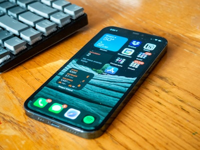 Phone on Desk - A smartphone and keyboard on a wooden desk