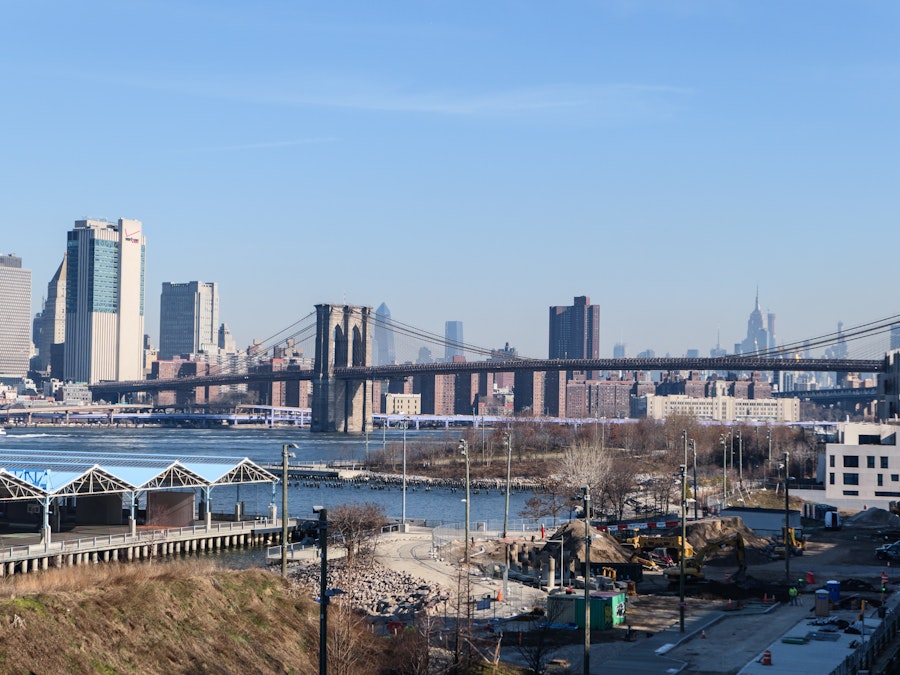 Photo: A bridge over water with buildings and city skyline in the background