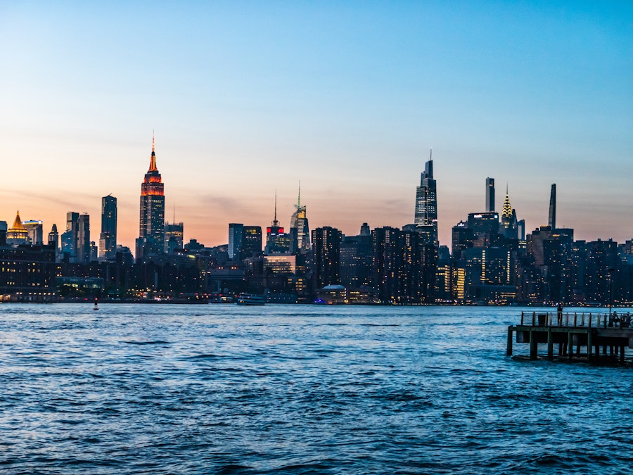 Photo: A city skyline with a dock in the water during sunset 