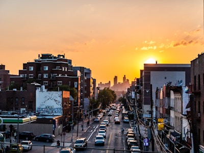 Sunset Over City Buildings and Street - A city street with cars and buildings with the sunset in the distance 