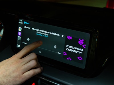 Person Playing Podcast in Car - A hand touching a touch screen in a car
