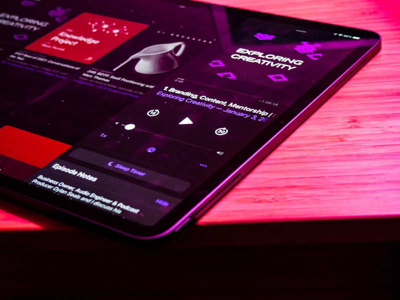 Photo: A tablet with a podcast playing on a wooden desk