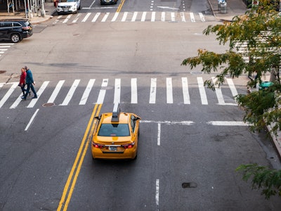 New York City Taxi on Street - A yellow taxi on a street with people crossing 