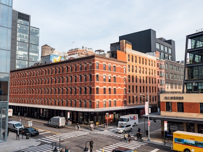 Manhattan Buildings and People - A large building with many windows on a city street with cars parked and people walking 