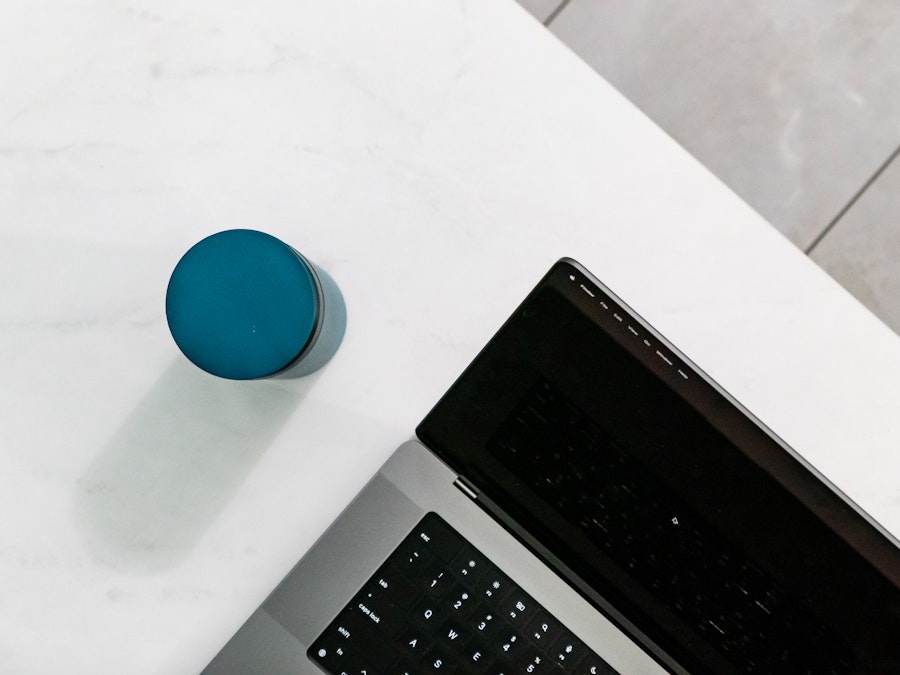 Photo: A tumbler and laptop on a white table at a coffee shop 