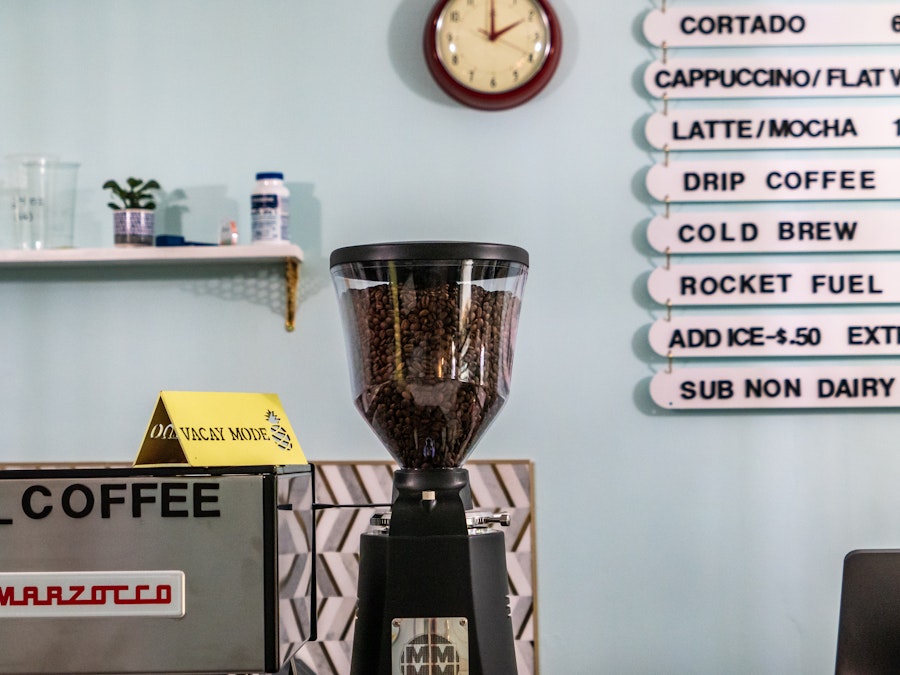 Photo: A coffee machine with beans in it and menu board at a coffee shop