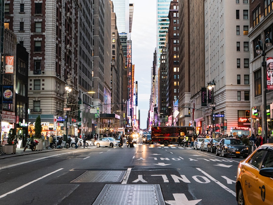 Photo: A city street with people, yellow taxis, cars and buildings in the background