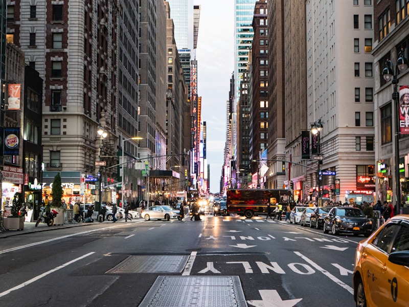 Photo: A city street with people, yellow taxis, cars and buildings in the background