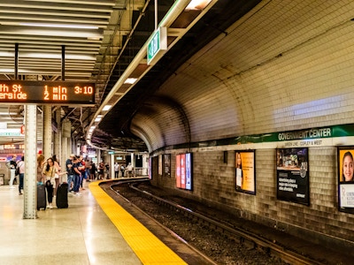 Boston Subway Station Platform - People standing in a train station with advertisements and a departures board