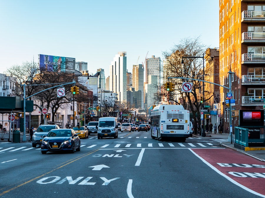 Photo: A city street with cars and buses, surrounded by buildings