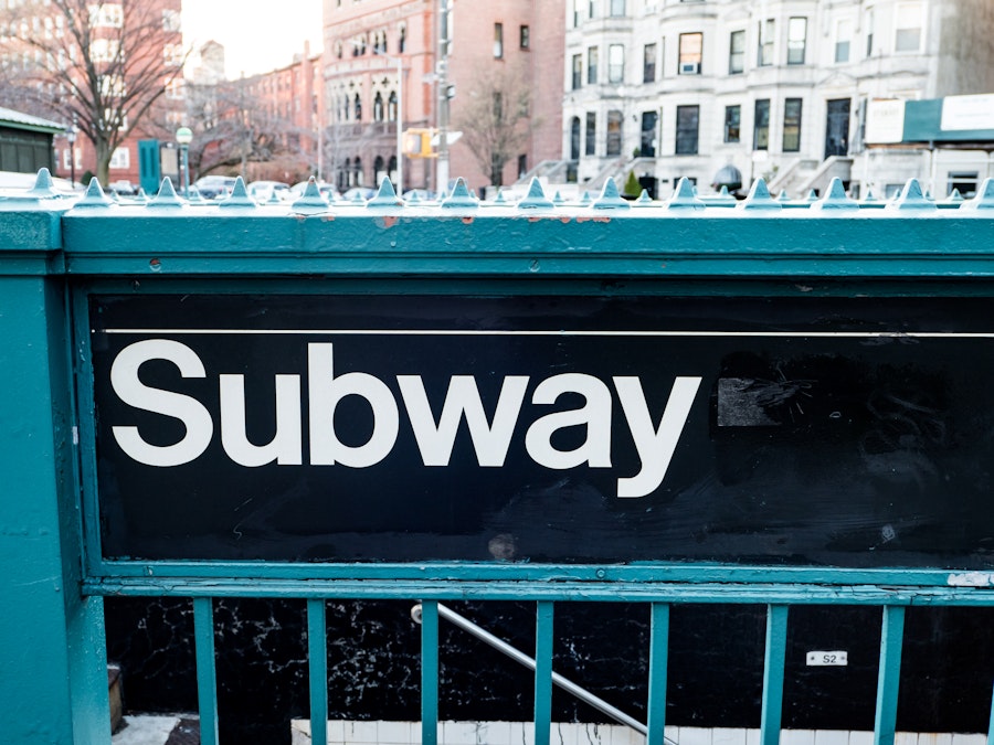 Photo: An entrance sign to the subway staircase on a fence railing
