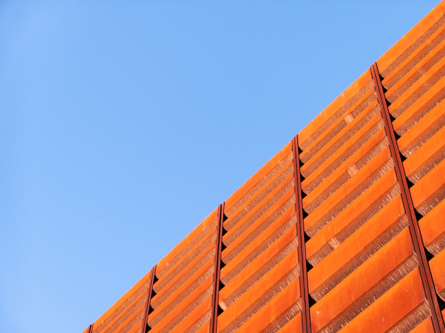 Photo: A close up of a wall on an orange building under blue sky 