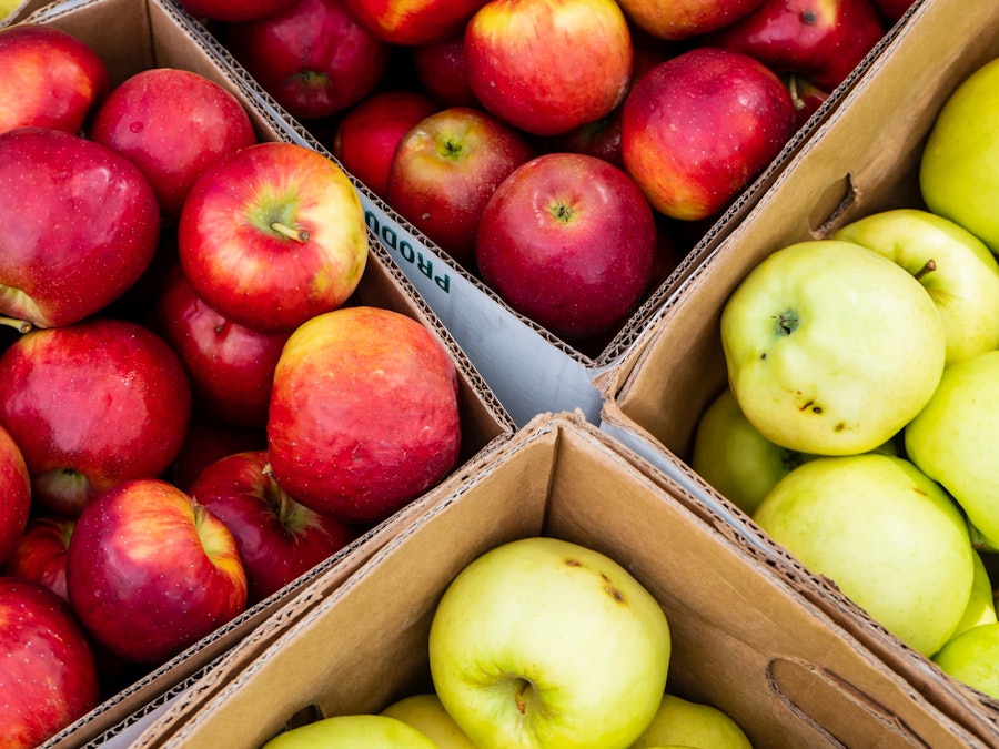 Photo: Boxes of red and yellow apples at a farmers market