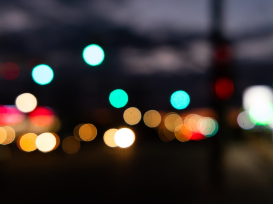 Photo: A blurry image of a street at night with car and streetlights shining