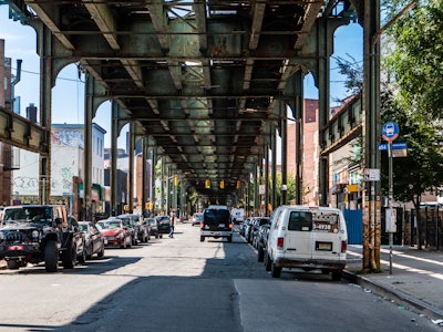 Bushwick Brooklyn Street Under Elevated Subway Tracks - Cars parked on a street under train tracks 