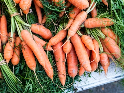 Carrots - A bunch of carrots with green leaves at a farmers market