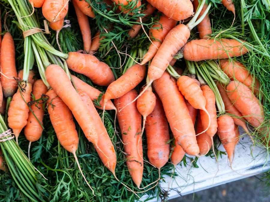 Photo: A bunch of carrots with green leaves at a farmers market