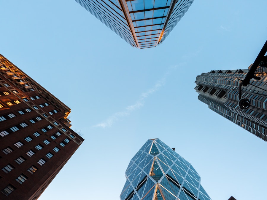 Photo: Looking up view of several tall buildings under blue sky