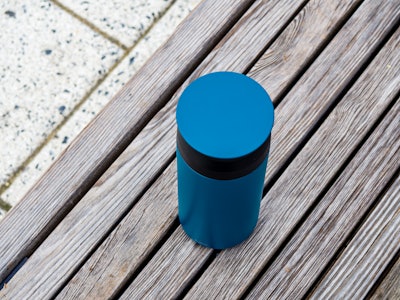 Coffee Tumbler on Wood Bench - A blue coffee tumbler on a wood chair in a park