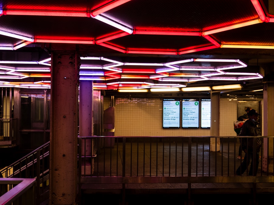 Photo: People standing in a subway station with lights above them