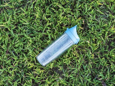 Water Bottle on Grass - A hard plastic water bottle on grass in a field 