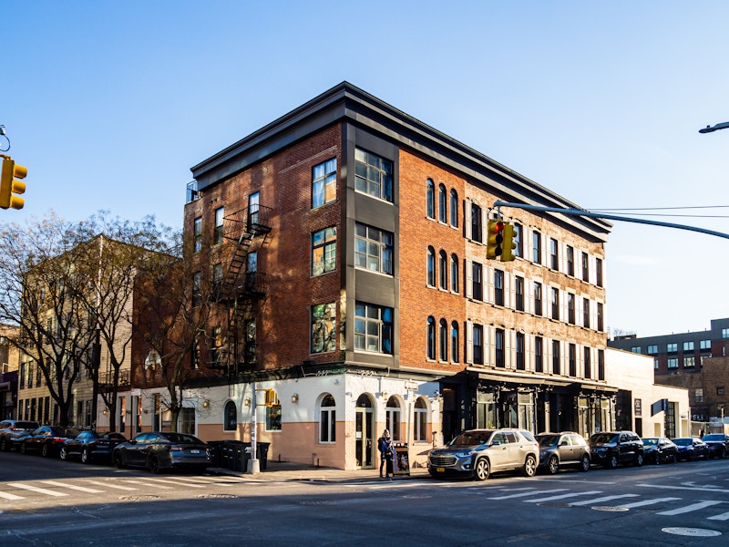 Photo: Buildings on a city street with cars parked on the side