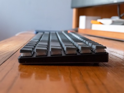 Keyboard on Desk - A keyboard on a wooden desk with a computer monitor above it
