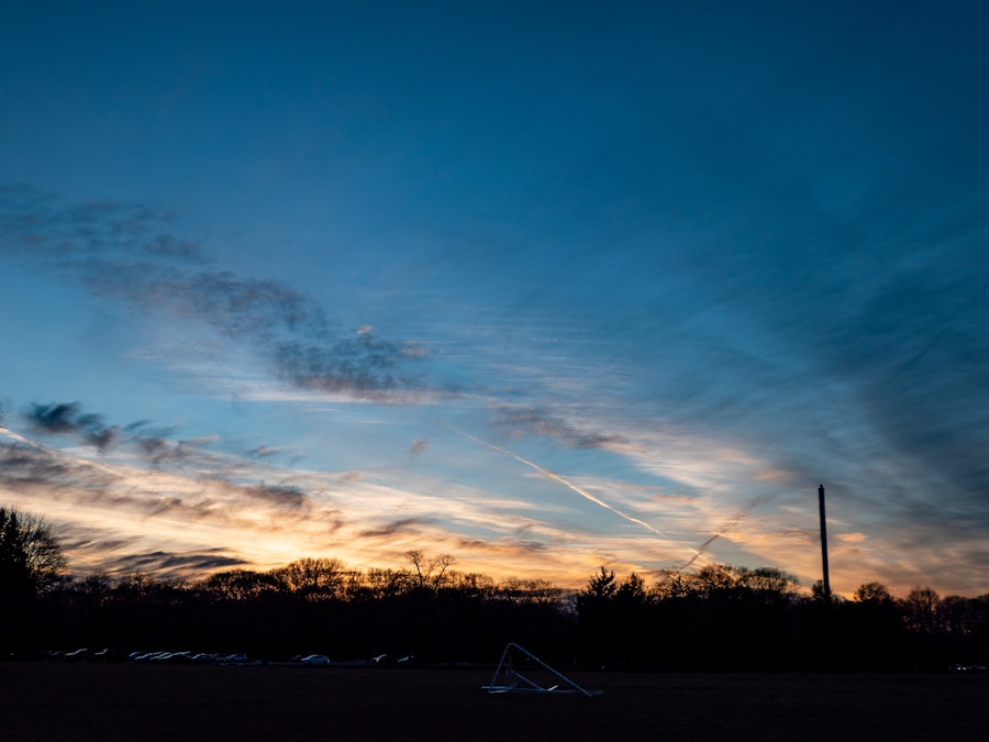 Photo: A sunset with silhouetted clouds and trees