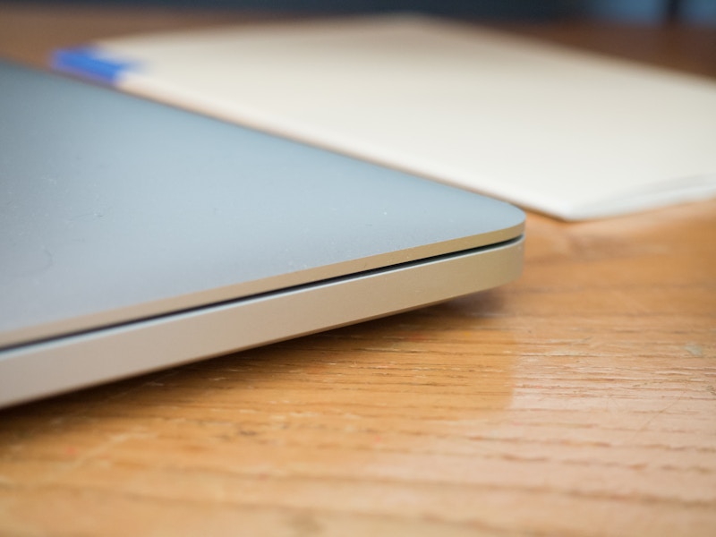 Photo: Side of Laptop on Desk with White Book