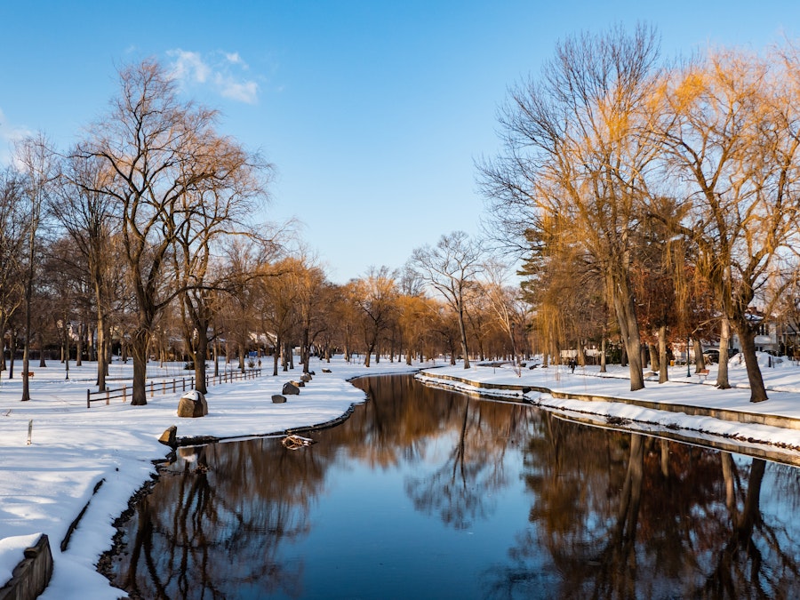 Photo: A body of water with snow and trees in a park