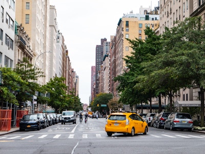 Manhattan Street with Taxi and Cyclist - A yellow taxi on a street with many cars and buildings