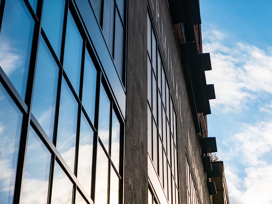 Photo: A building with windows on the side reflecting the sky and clouds