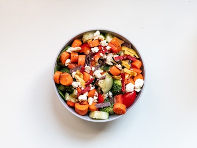 Colorful Fresh Salad in Bowl - A bowl of salad with vegetables and cheese on a white desk