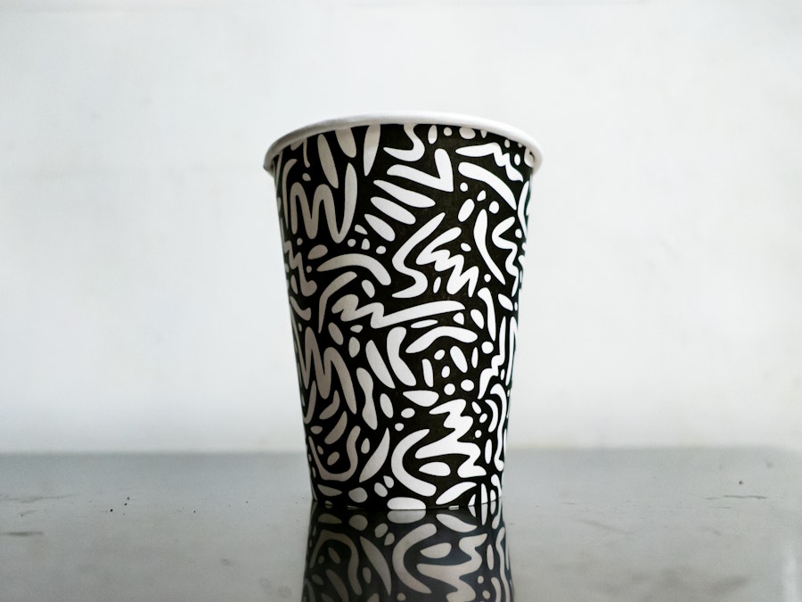 Photo: A black and white cup with an illustrated white pattern on it